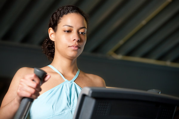 Image shows a young woman doing an intense workout using training zones to maximise her workout intensity on a piece of gym equipment.